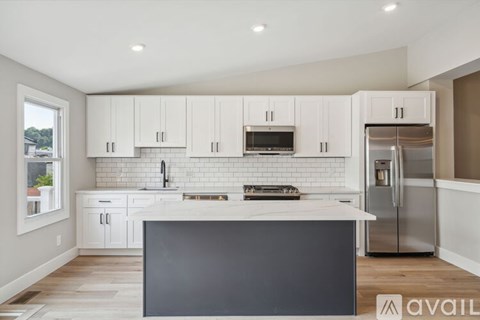 A kitchen with white cabinets and a black island.