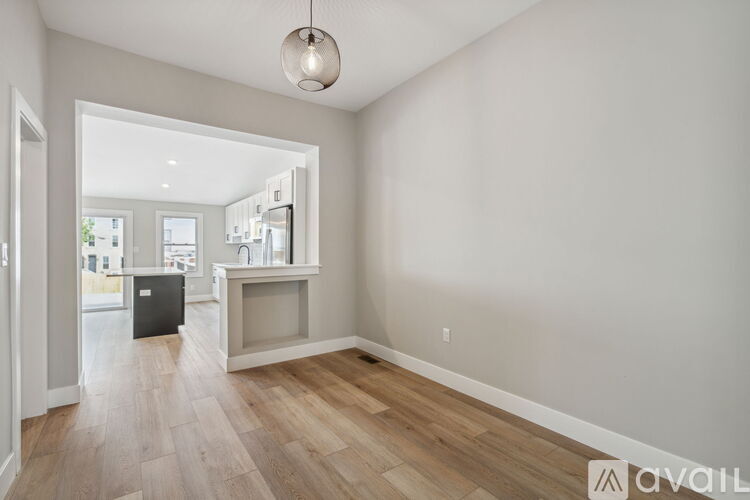 A spacious room with wooden flooring and a large window.