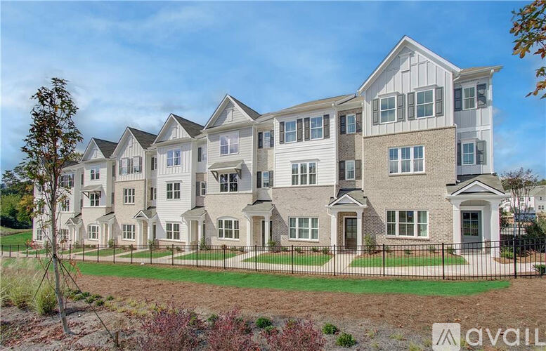 A large, multi-story residential building with a black fence in front.