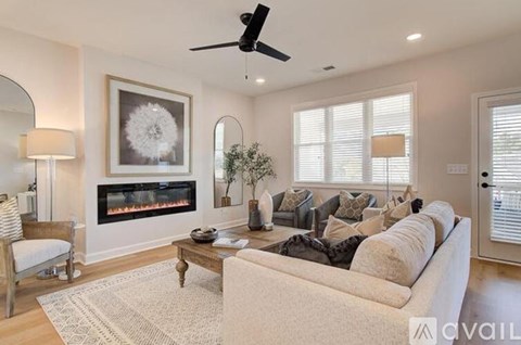 A living room with a fireplace, a couch, and a ceiling fan.