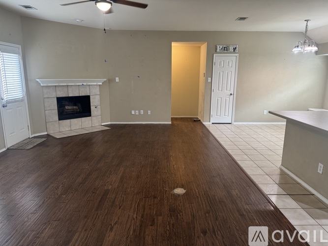 A spacious living room with wood flooring and a fireplace.