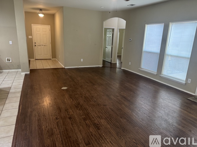 A spacious room with wooden flooring and a doorway leading to another room.