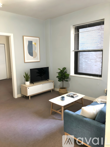 A living room with a blue couch, a white coffee table, and a television.