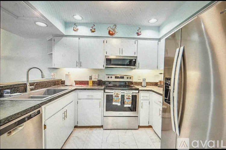 A kitchen with white cabinets and a stainless steel refrigerator.