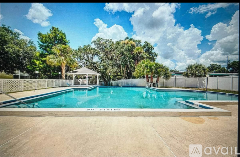 A pool surrounded by a fence with a gazebo in the background.