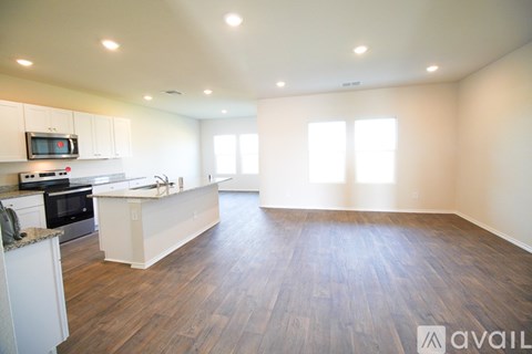 A spacious kitchen and living room with wooden floors and white walls.