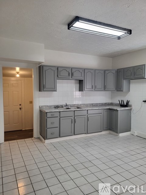 A kitchen with grey cabinets and a white tiled floor.