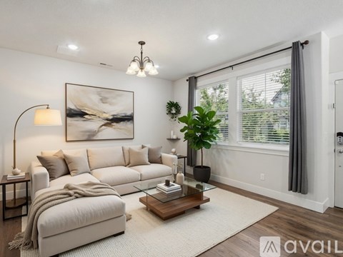 A living room with a large couch, a coffee table, and a painting on the wall.