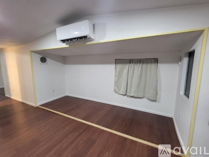 A room with a window covered by a curtain and a wall-mounted air conditioner.