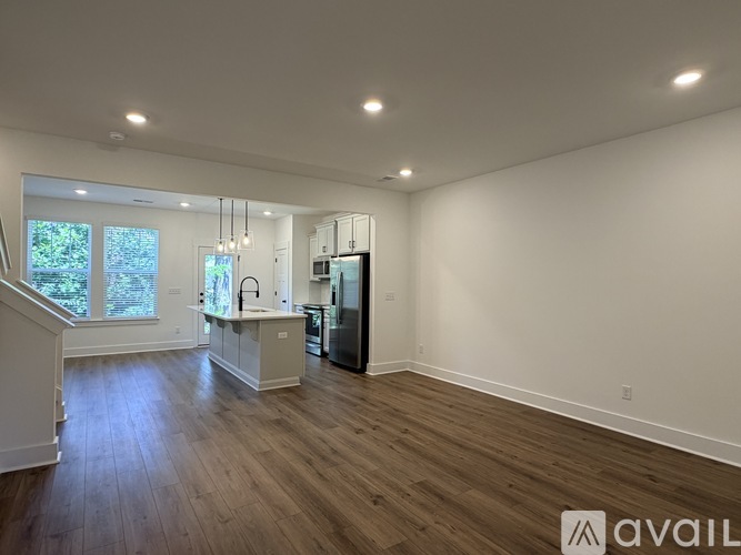 A spacious kitchen with wooden floors and a refrigerator.