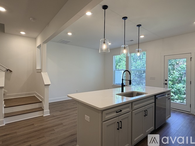 A modern kitchen with a large island and pendant lights.