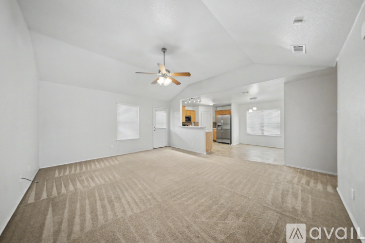 A spacious room with a carpeted floor and a ceiling fan.