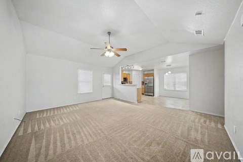 A spacious room with a carpeted floor and a ceiling fan.