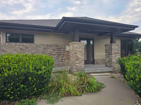 A house with a grey front porch and a stone wall.