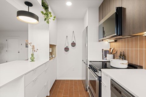 A modern kitchen with white cabinets and a black stove top.