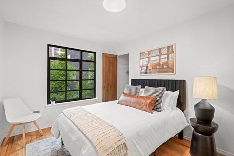 A bedroom with a large bed and a chair.