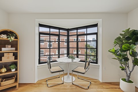 A dining room with a table and chairs and a potted plant.