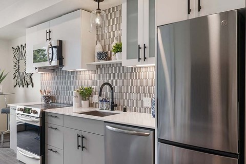 A modern kitchen with a stainless steel refrigerator and a backsplash of rectangular tiles.