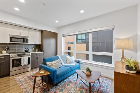 A blue couch sits in a living room with a wooden coffee table in front of it.