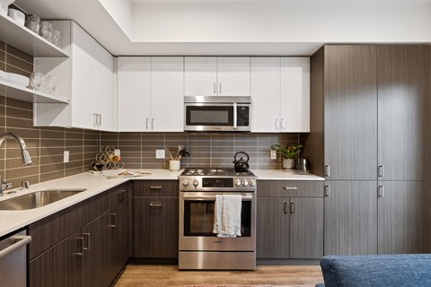 A modern kitchen with dark wood cabinets and stainless steel appliances.
