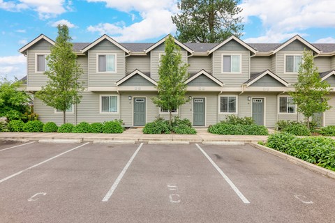A parking lot in front of a building with grey houses.