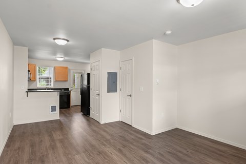 A kitchen with white walls and wooden floors.