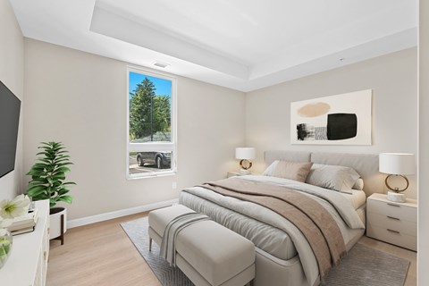 A bedroom with a large bed and a picture of a tree on the wall.