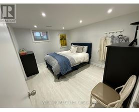 A bedroom with a bed, chair, and a painting on the wall.