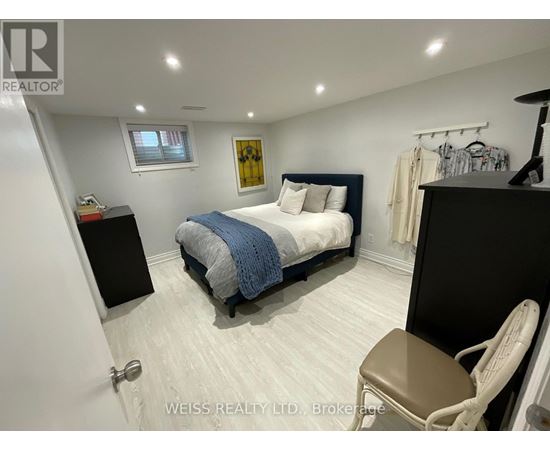 A bedroom with a bed, chair, and a painting on the wall.