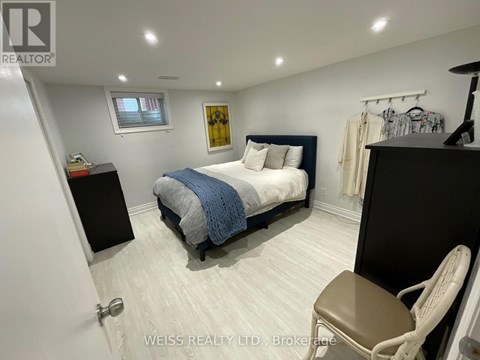 A bedroom with a bed, chair, and a painting on the wall.
