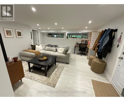 A well-lit living room with a couch, coffee table, and a wall-mounted coat rack.