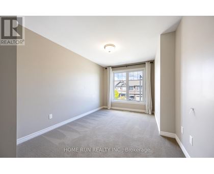 A room with a carpeted floor and a window with a view of a building outside.