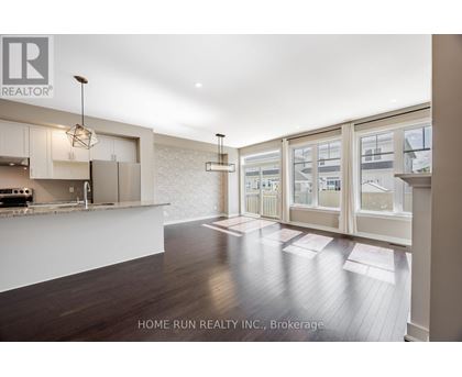 A modern kitchen with white cabinets and a wooden floor.