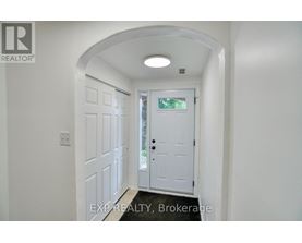 A white door is in a hallway with a light on the ceiling.