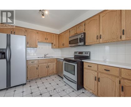 A kitchen with wooden cabinets and a black and white tiled floor.