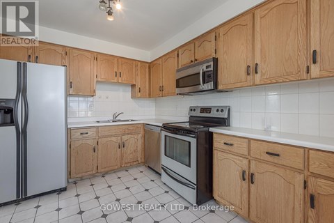 A kitchen with wooden cabinets and a black and white tiled floor.
