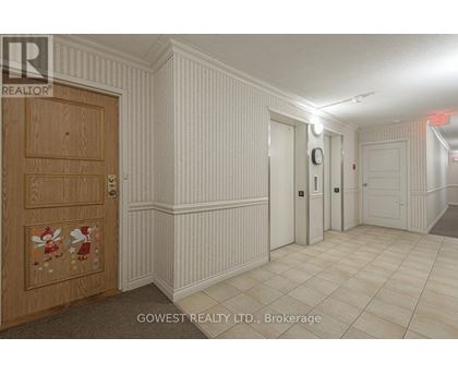 A hallway with a wooden door on the left and a tiled floor.