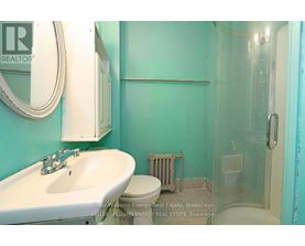 A bathroom with a sink, toilet and glass shower stall.