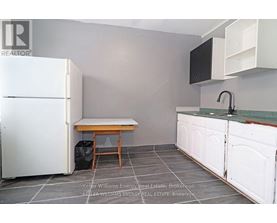 A kitchen with a white fridge, a table and a sink.