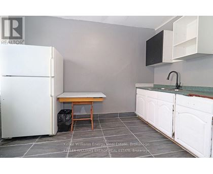 A kitchen with a white fridge, a table and a sink.