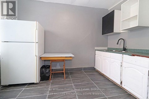 A kitchen with a white fridge, a table and a sink.