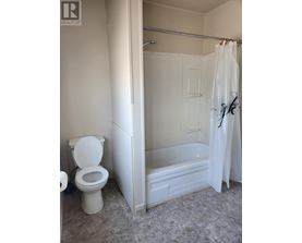 A white toilet is in a bathroom with a white shower curtain.