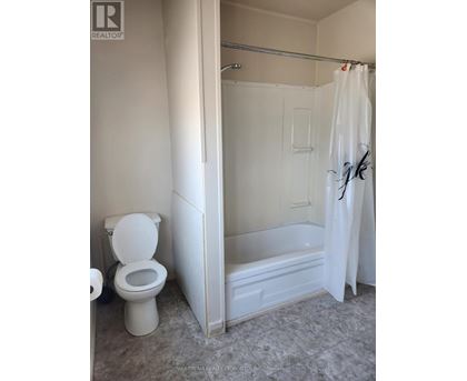 A white toilet is in a bathroom with a white shower curtain.
