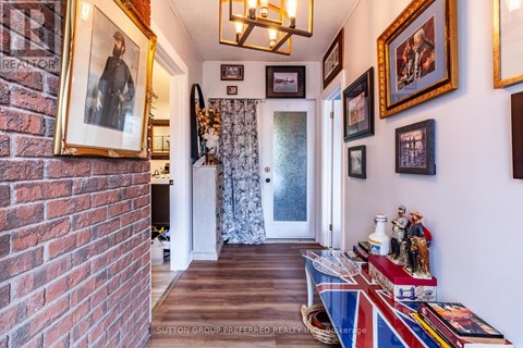 A hallway with a brick wall on the left and a series of framed pictures on the wall.