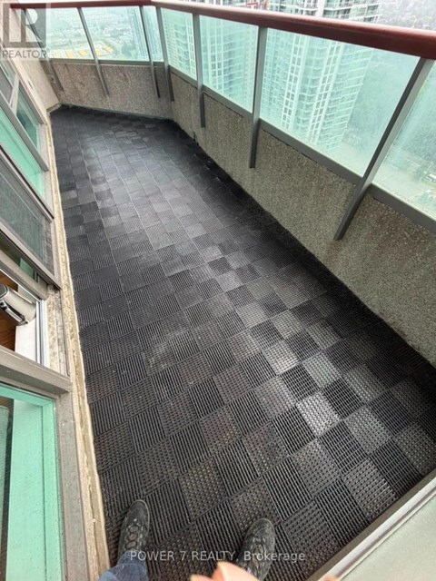 A person is standing on a black tiled floor with glass walls on the sides.