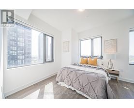 A bedroom with a large bed and a city view through the window.