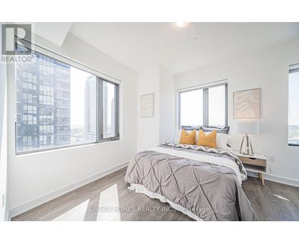 A bedroom with a large bed and a city view through the window.