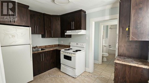 A kitchen with white appliances and brown cabinets.