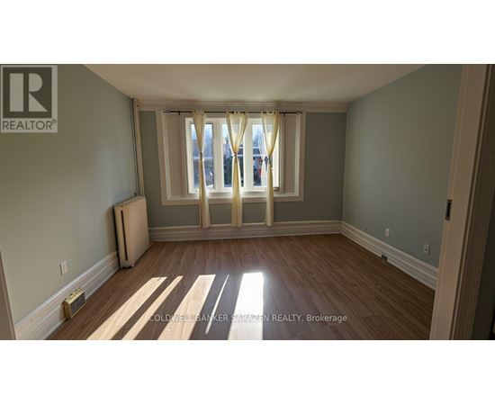 A room with wooden floors and a window with curtains.