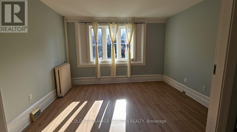 A room with wooden floors and a window with curtains.